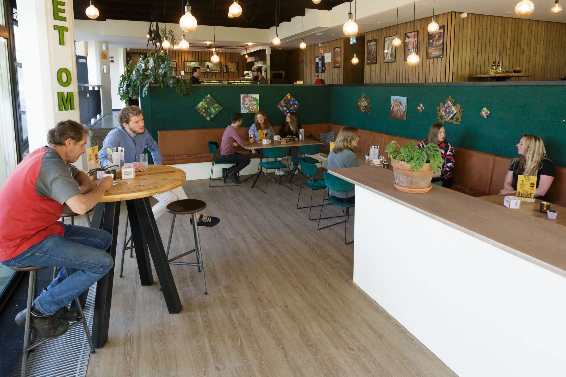 Cozy, modern escape room reception area with guests at tables.