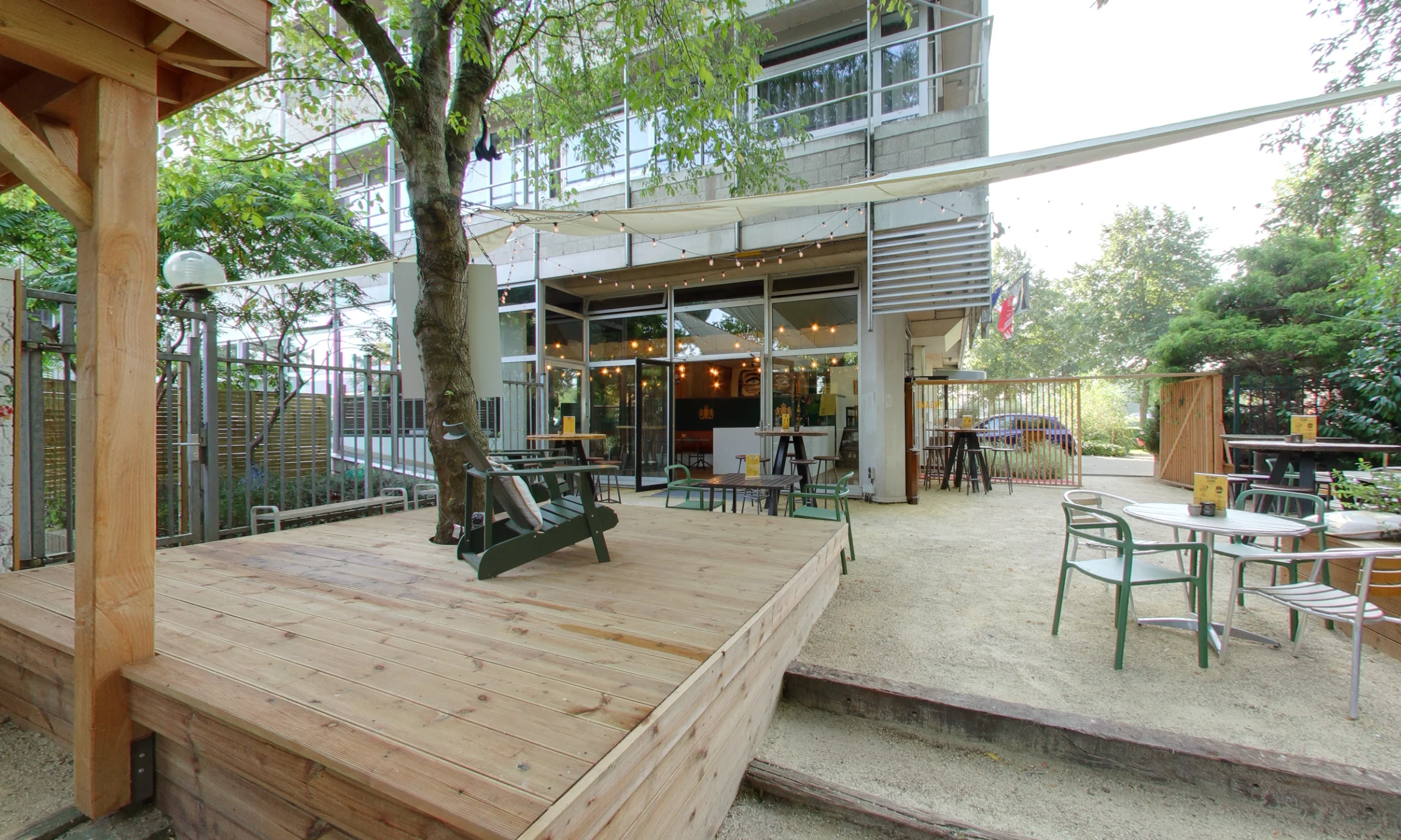 Atmospheric terrace with wooden decking, lounge chair, tables, and greenery.