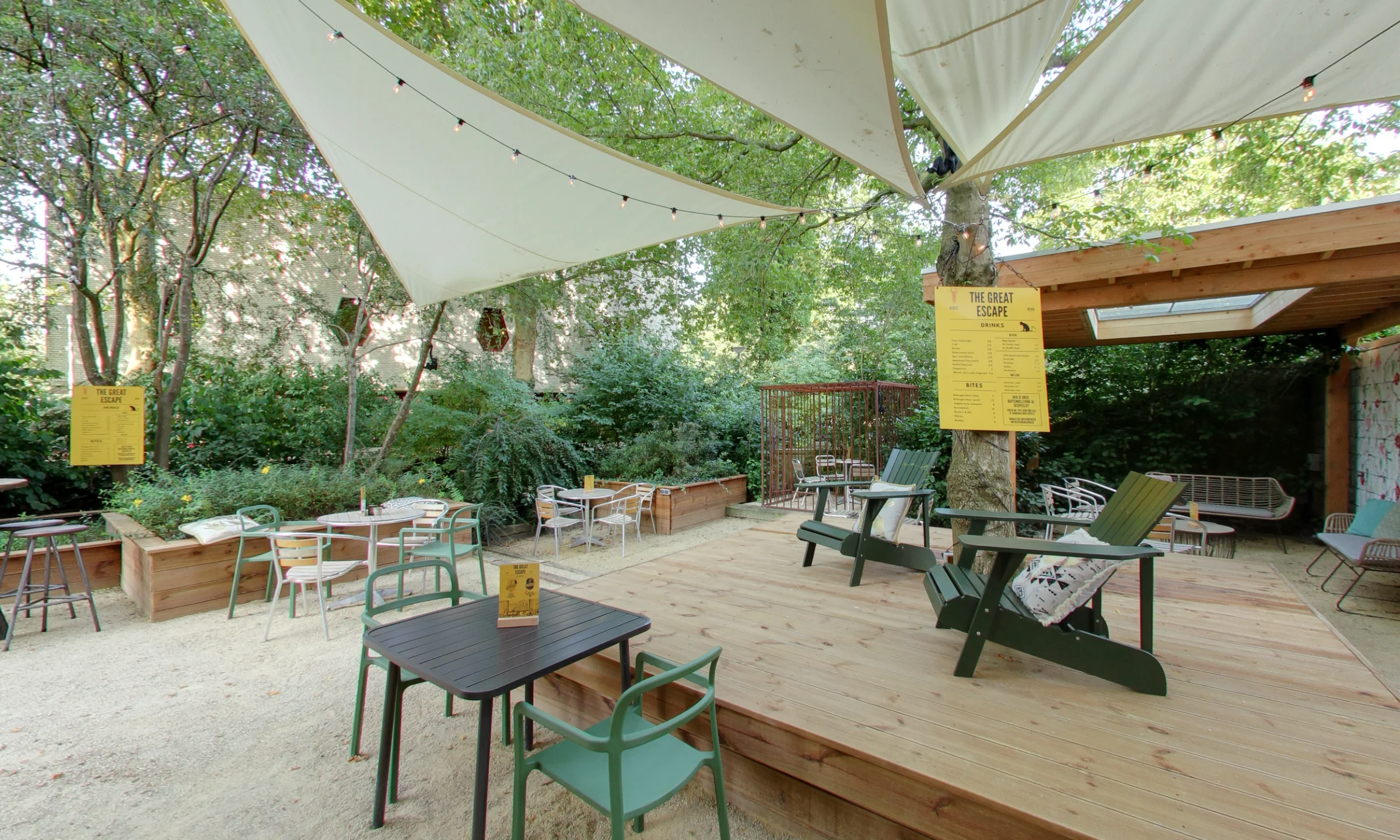 Cozy outdoor terrace with wooden decking and green chairs among trees.