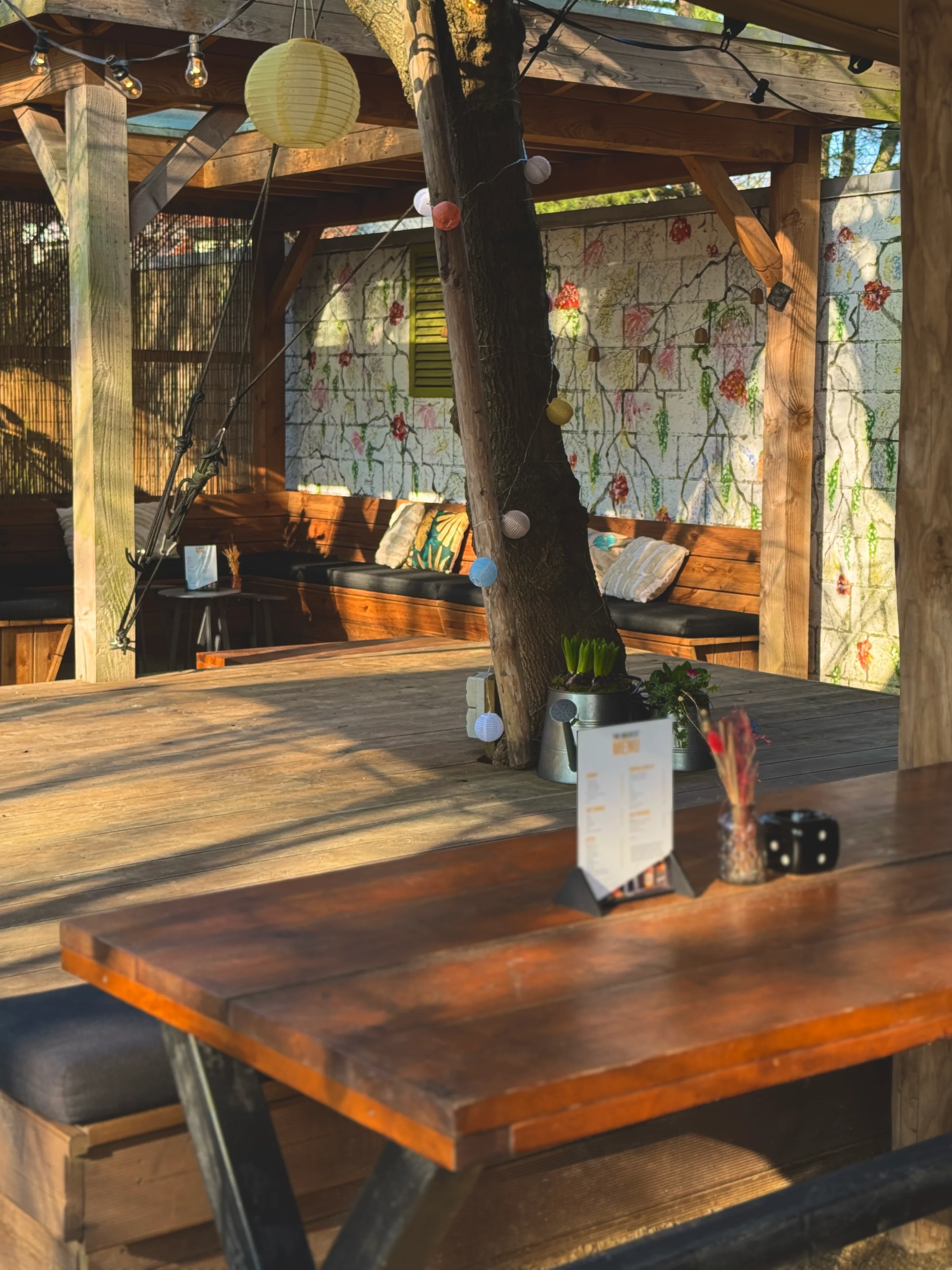 Cozy terrace with wooden furniture, atmospheric lighting, and plants.